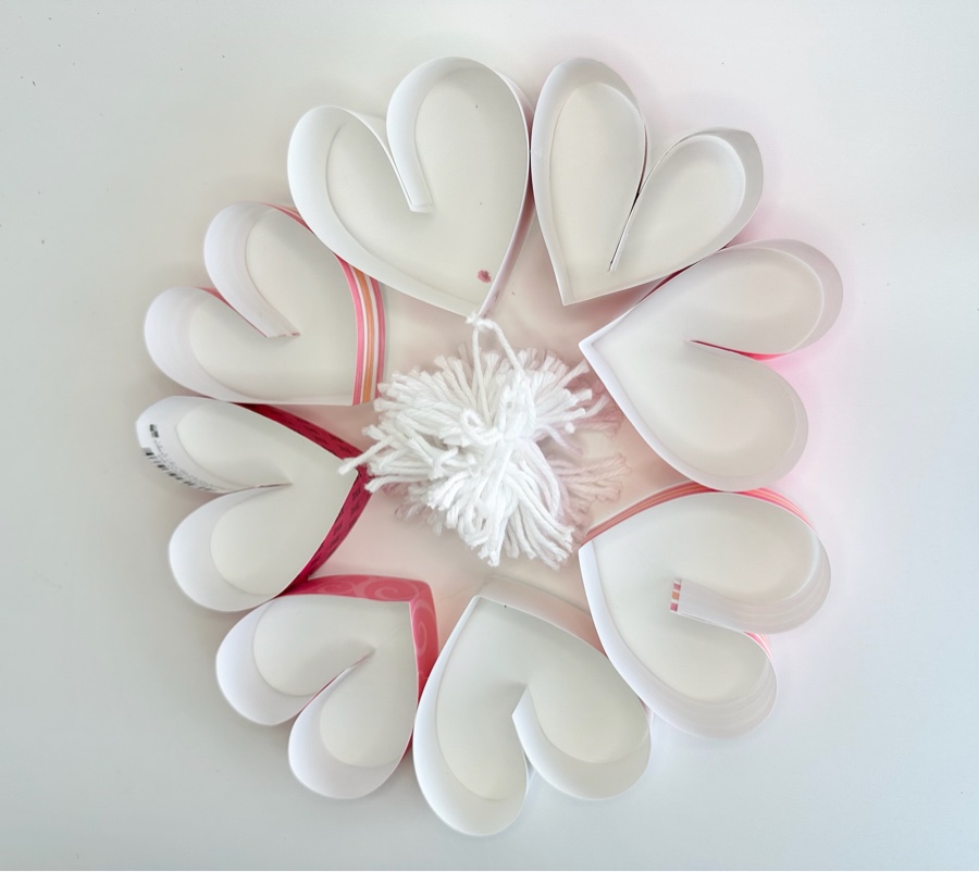 Handmade paper heart wreath with a white yarn pom-pom
